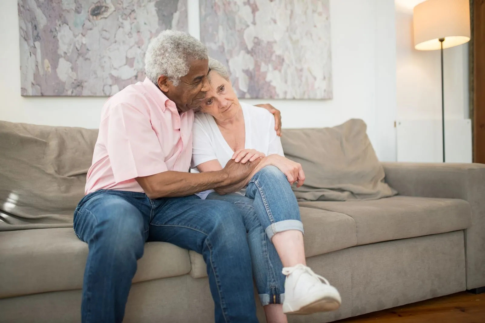 An older couple sitting close together on a sofa at home